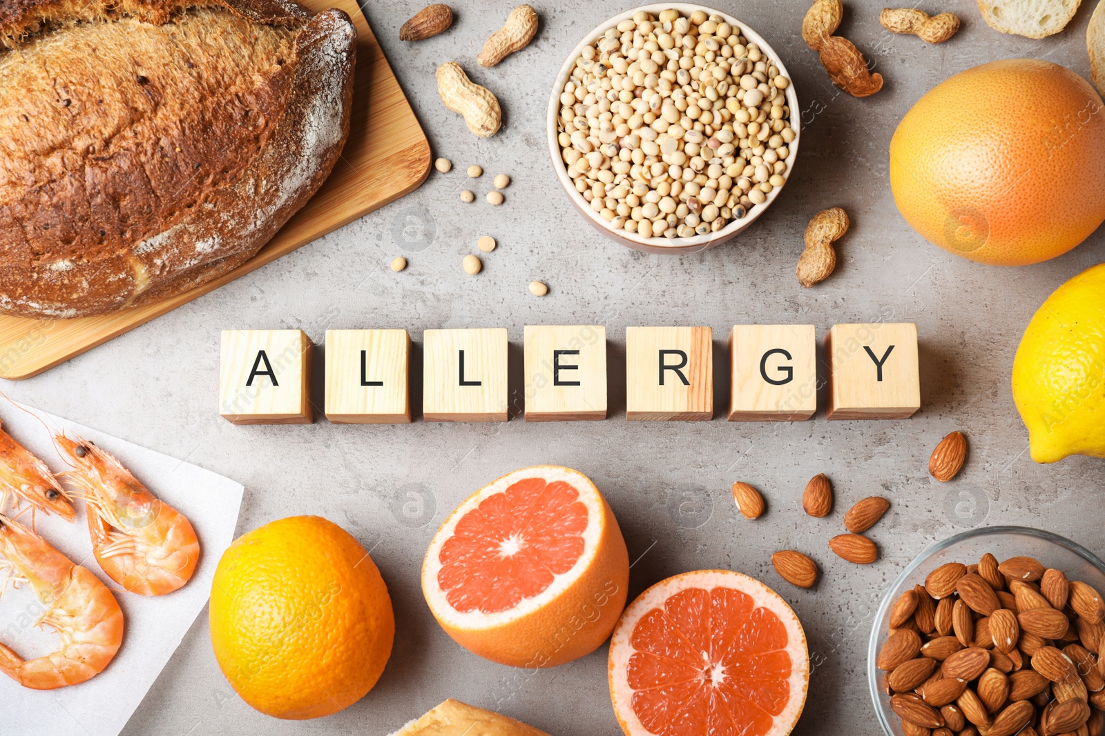 Photo of Flat lay composition of various foods and wooden cubes with word Allergy on gray table