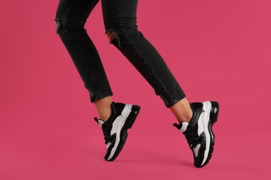 Woman wearing sneakers on pink background, closeup