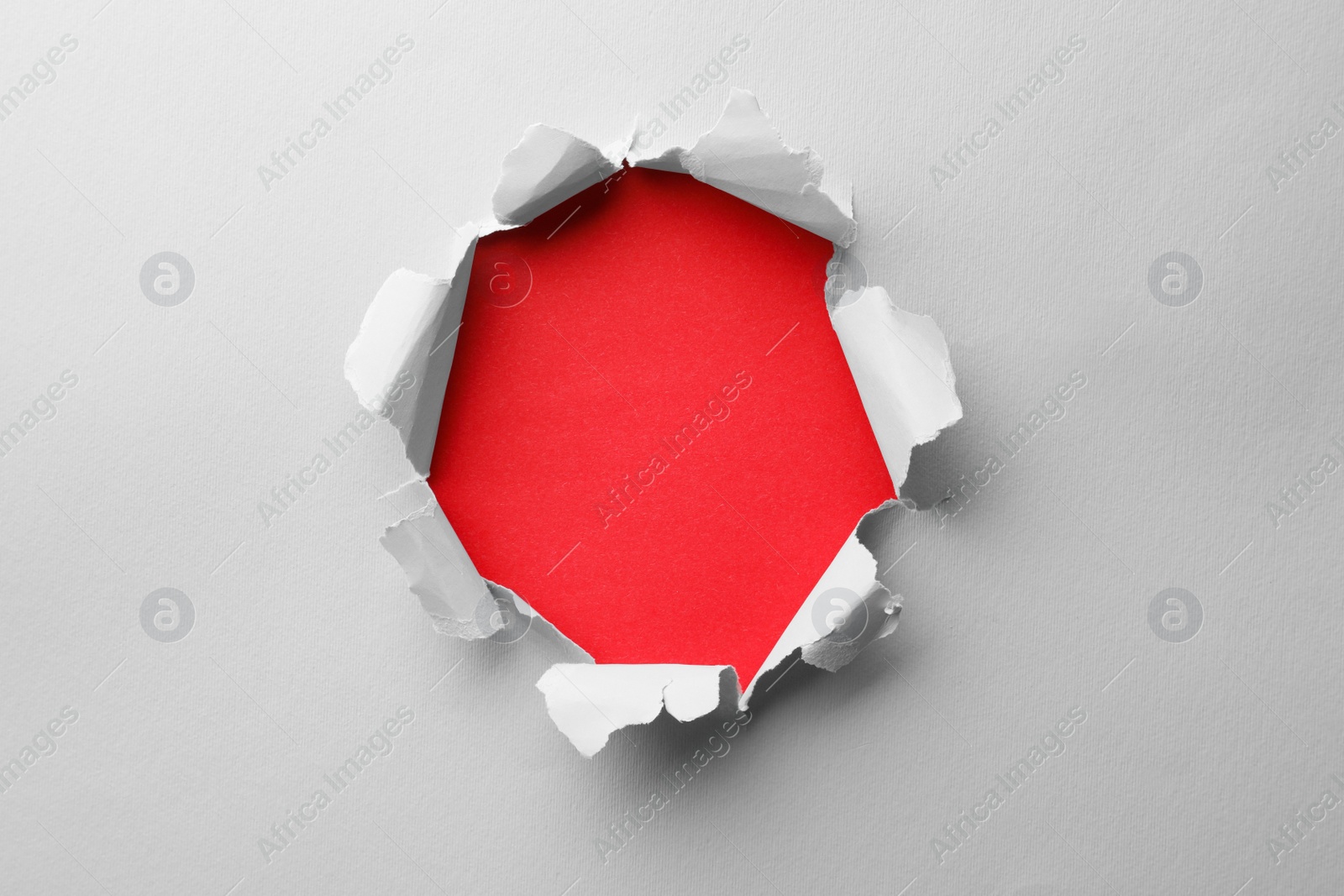 Photo of Hole in white paper on red background