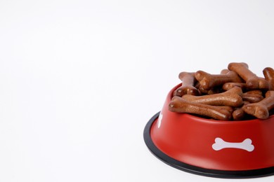 Red bowl with bone shaped dog cookies on white background, space for text