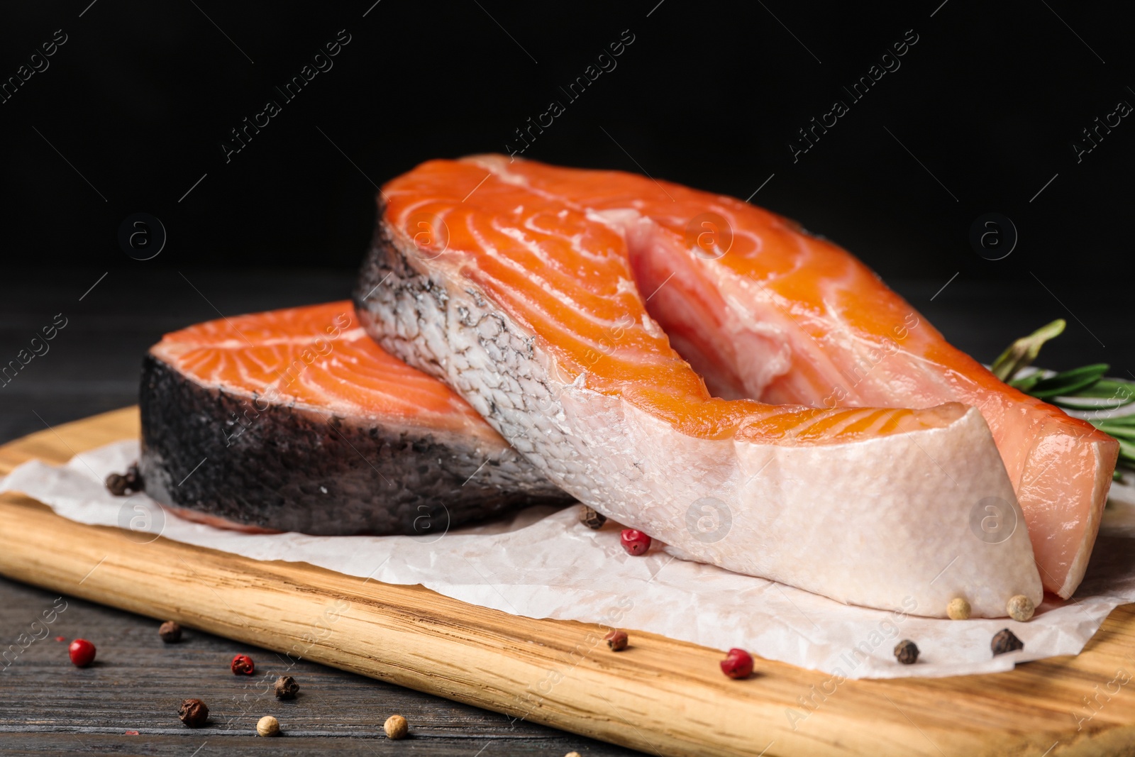 Photo of Fresh salmon steaks with spices on black wooden table
