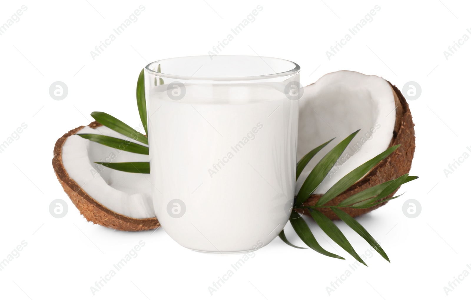 Photo of Glass of delicious vegan milk, coconut pieces and green leaves on white background