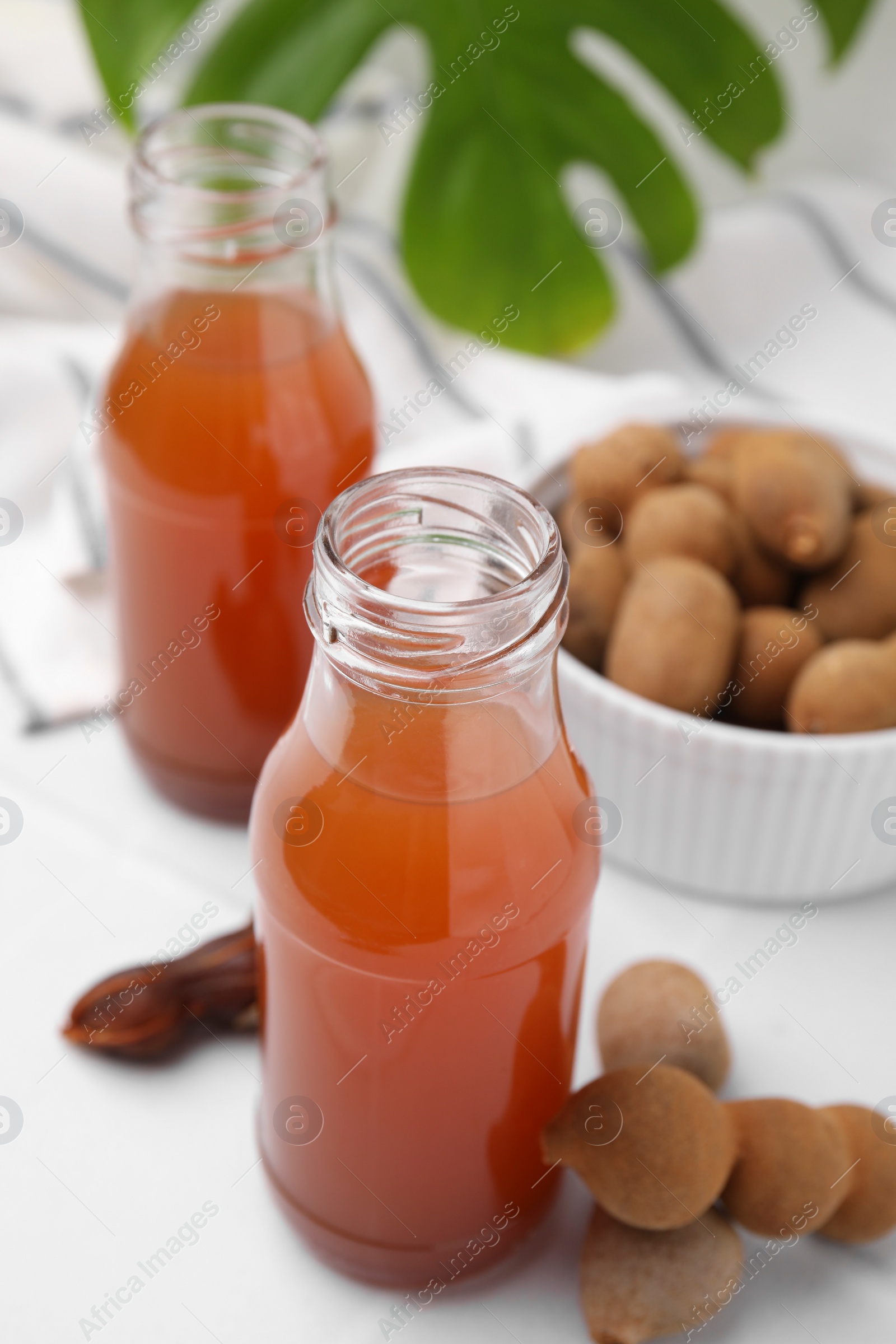 Photo of Tamarind juice and fresh fruits on white table, closeup