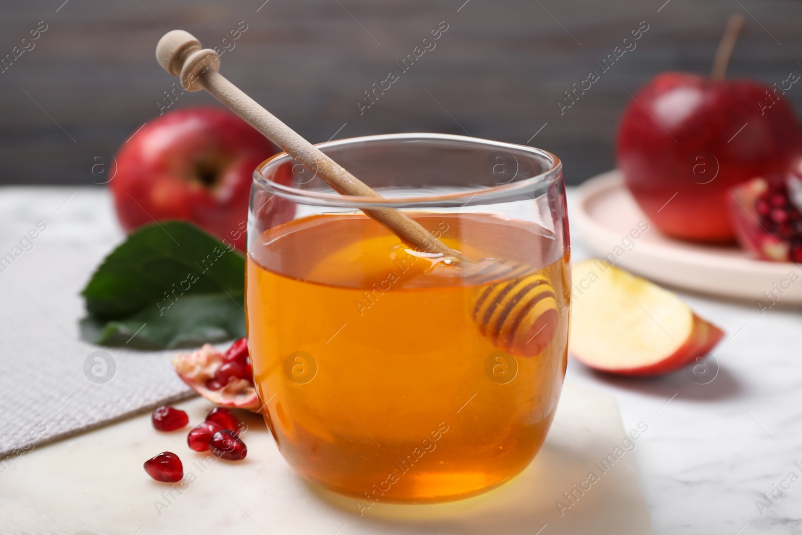 Photo of Honey, apples and pomegranate seeds on white marble table. Rosh Hashanah holiday