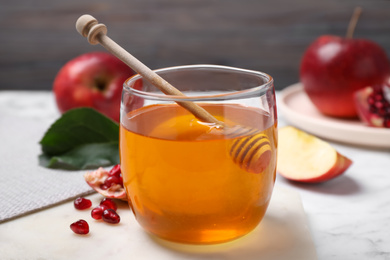 Photo of Honey, apples and pomegranate seeds on white marble table. Rosh Hashanah holiday