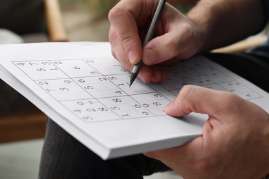 Photo of Man solving sudoku puzzle indoors, closeup view