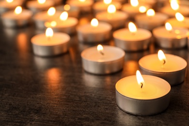 Photo of Burning candles on wooden table, space for text. Symbol of sorrow