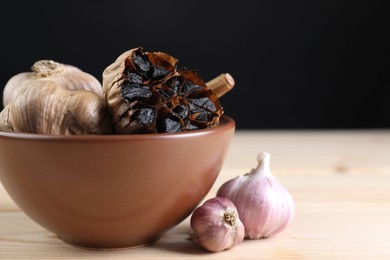 Photo of Fresh and fermented black garlic on wooden table