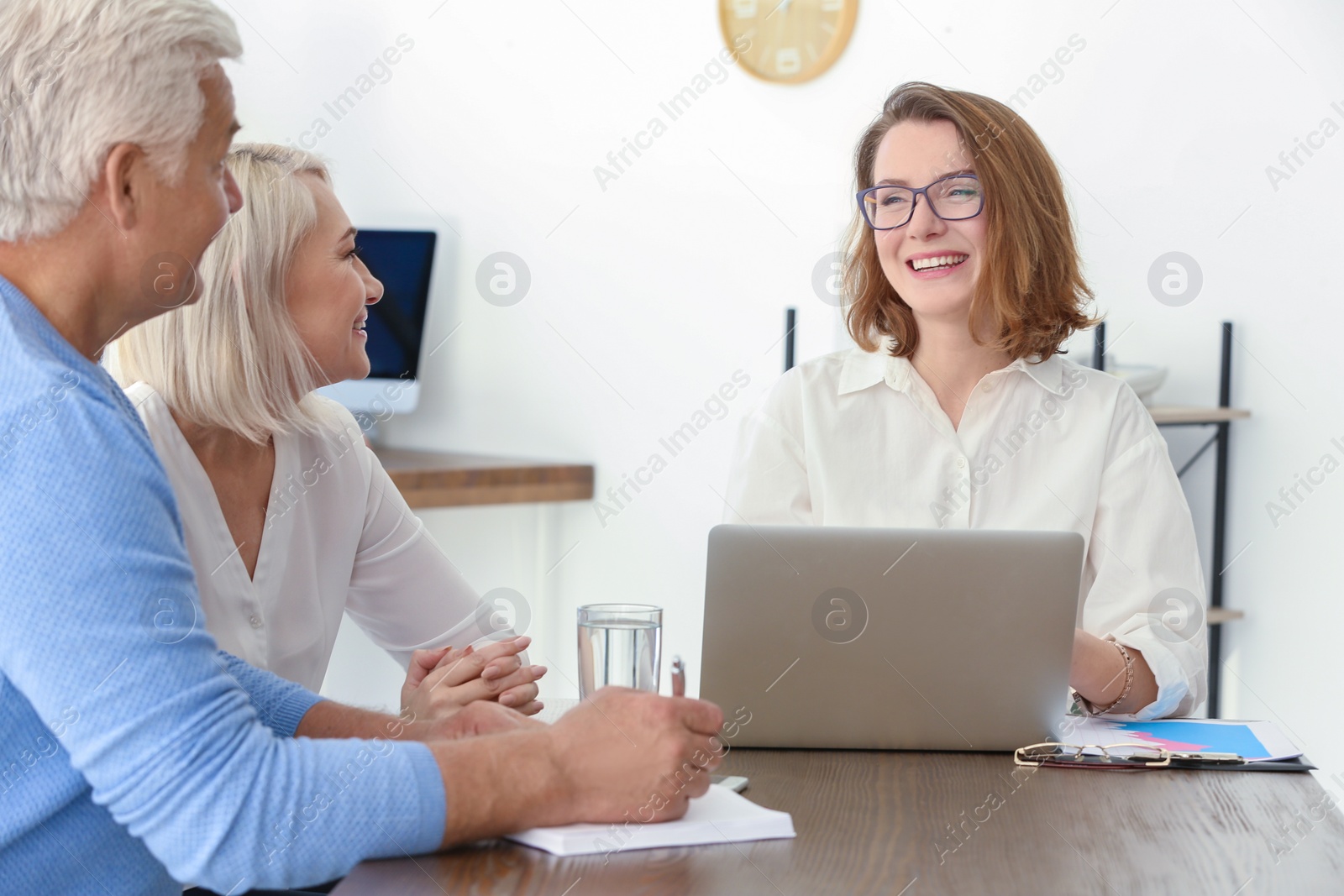 Photo of Female manager consulting mature couple in office