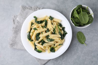 Photo of Tasty pasta with spinach and sauce on grey textured table, flat lay