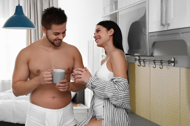 Photo of Young couple in white underwear drinking coffee at home