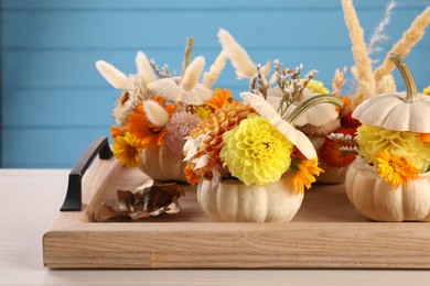 Photo of Composition with small pumpkins, beautiful flowers and spikelets on light wooden table, closeup
