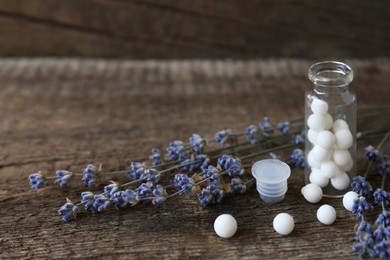 Photo of Bottle with homeopathic remedy and lavender flowers on wooden table. Space for text