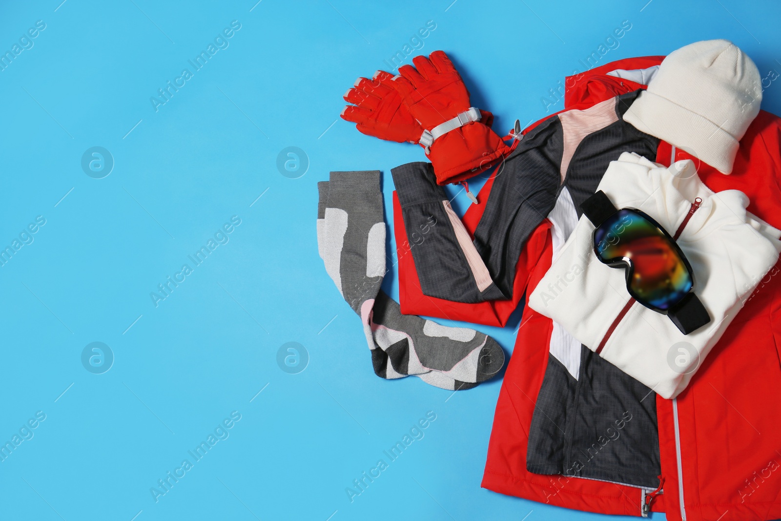 Photo of Stylish winter sport clothes on light blue background, flat lay. Space for text