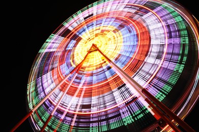 Beautiful glowing Ferris wheel against dark sky, low angle view