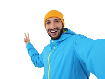 Photo of Smiling young man taking selfie and showing peace sign on white background