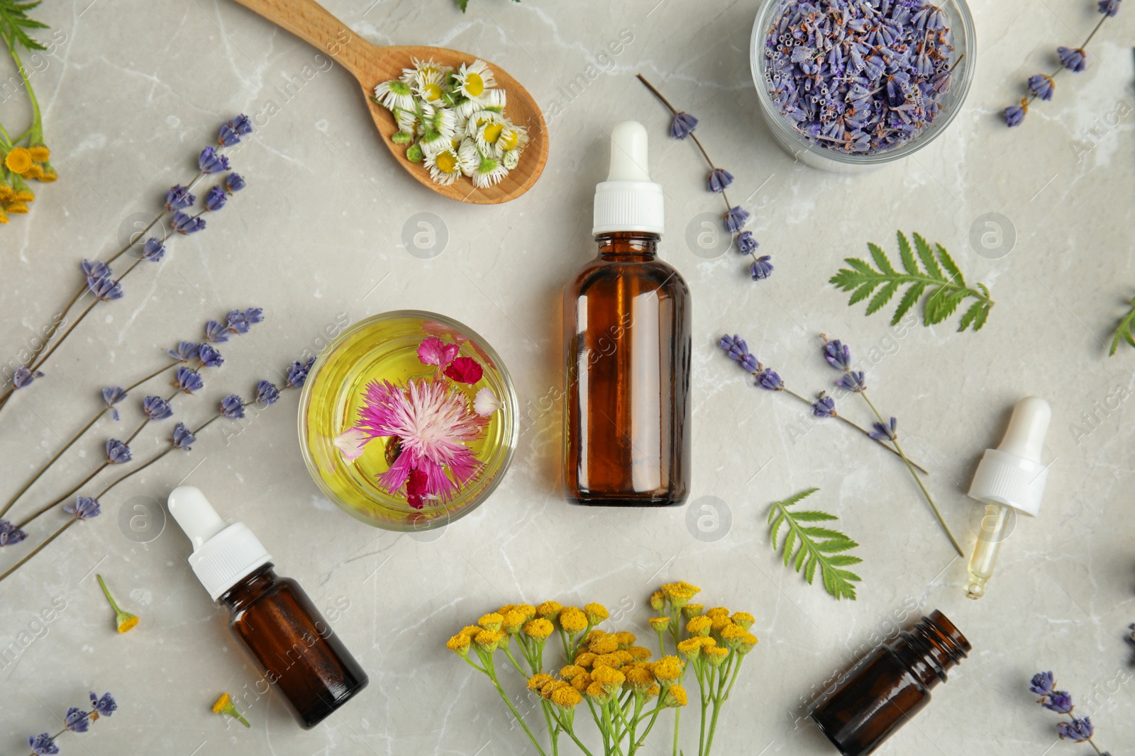 Photo of Flat lay composition with essential oils and flowers on light background