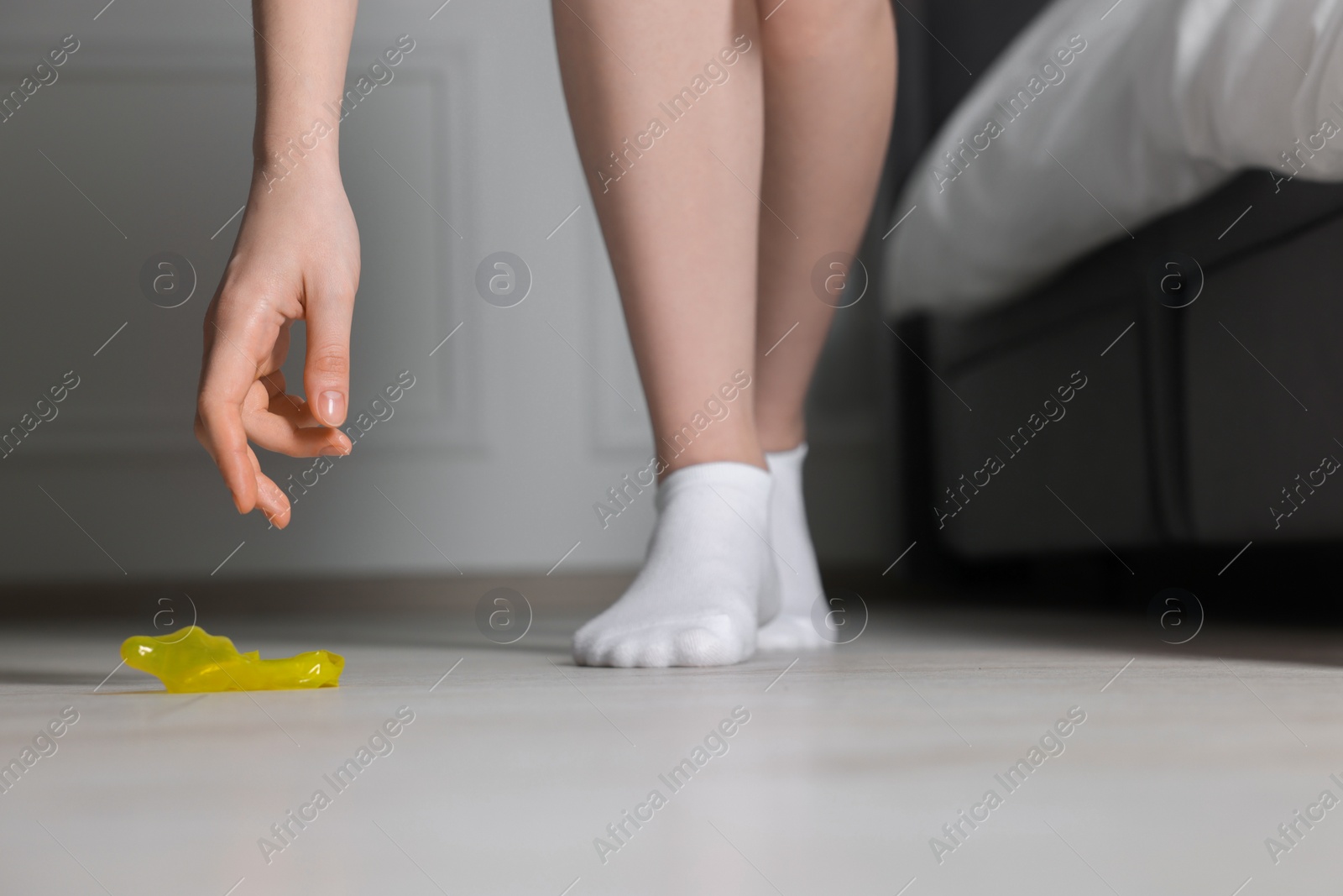 Photo of Woman taking unrolled condom from floor indoors, closeup. Safe sex