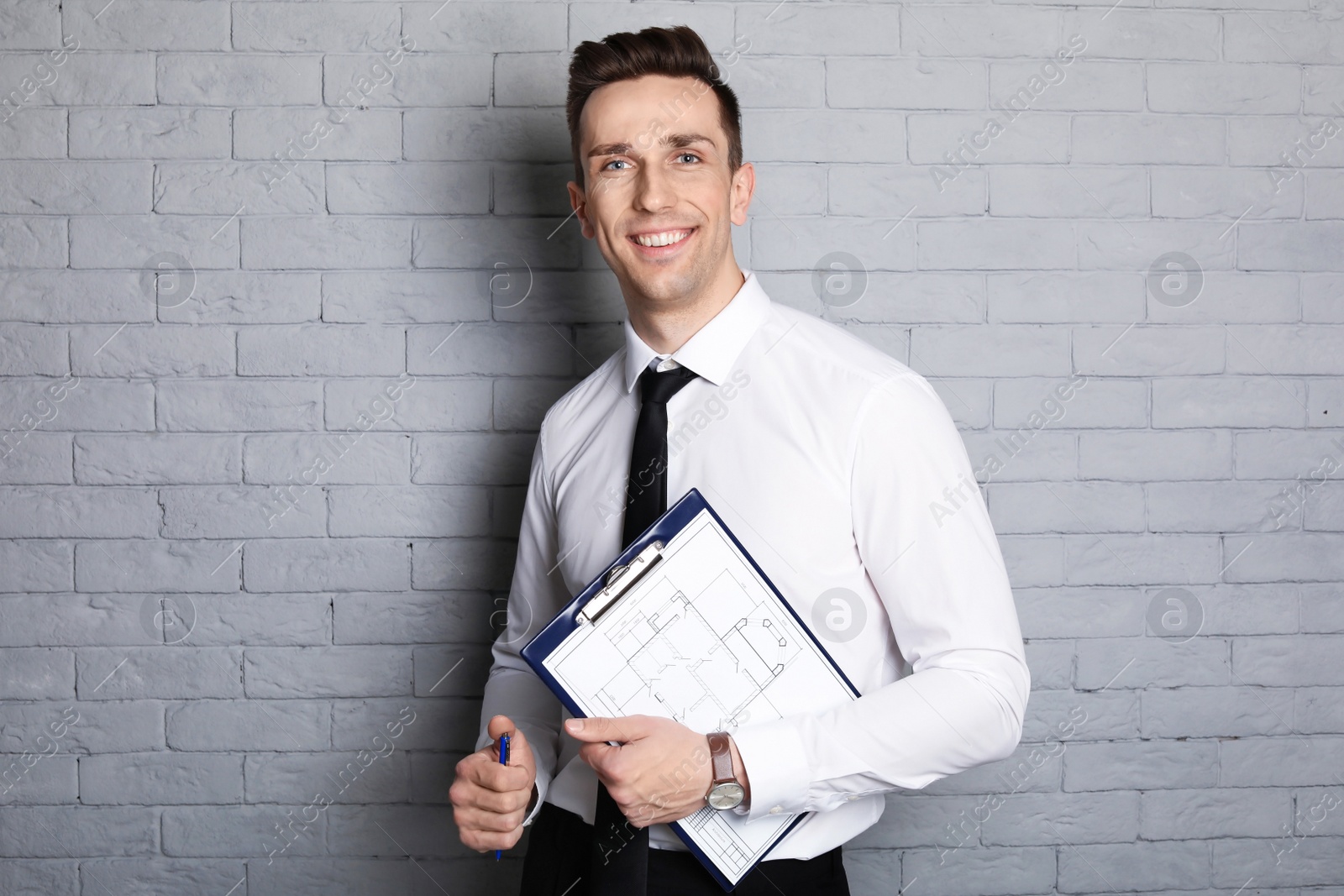 Photo of Male real estate agent with clipboard on brick wall background