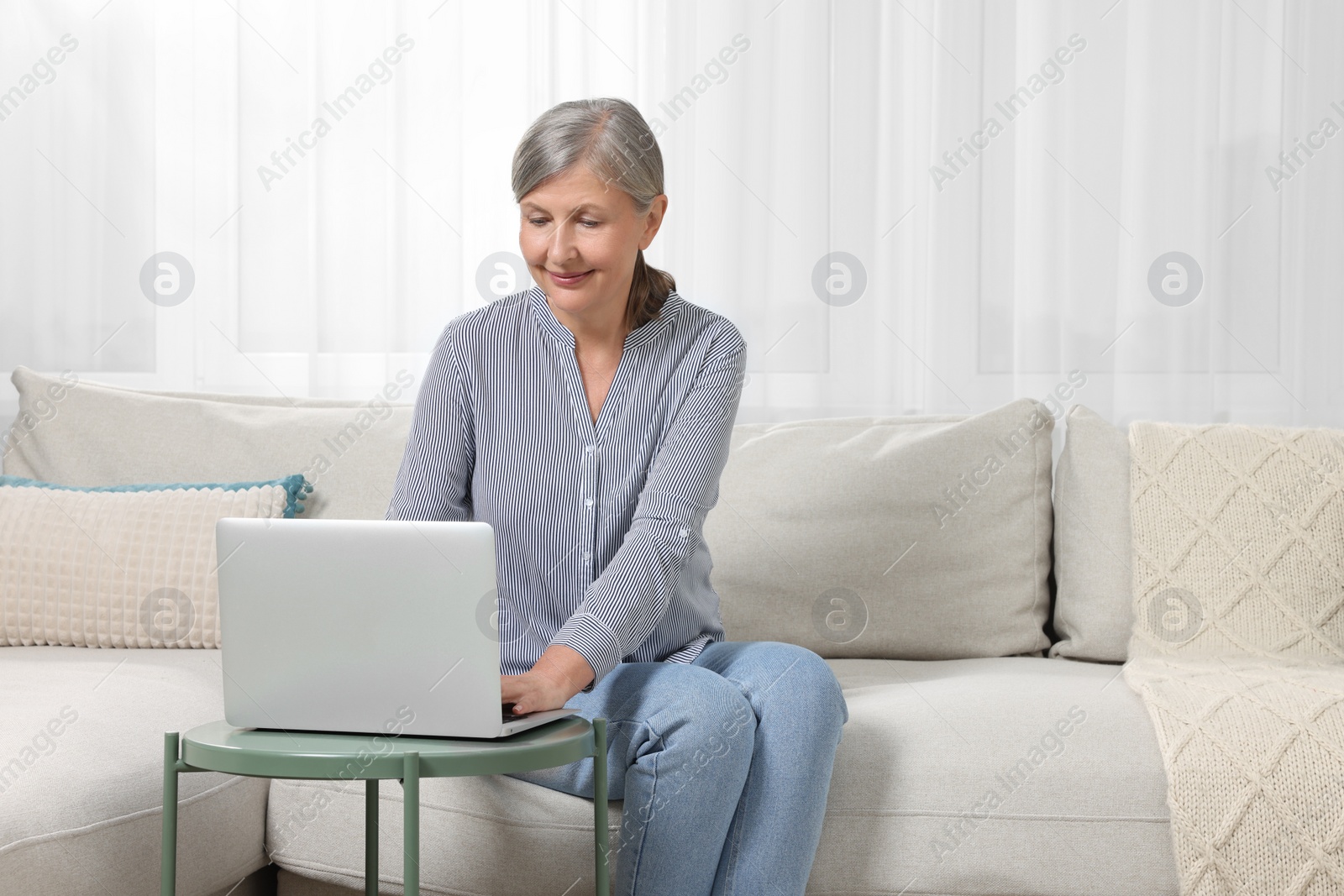 Photo of Beautiful senior woman using laptop at home, space for text