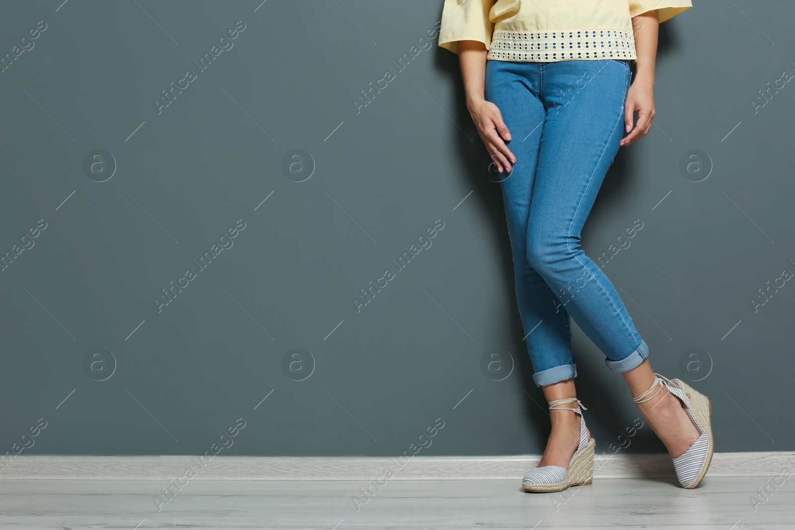 Photo of Young woman with sexy legs near grey wall