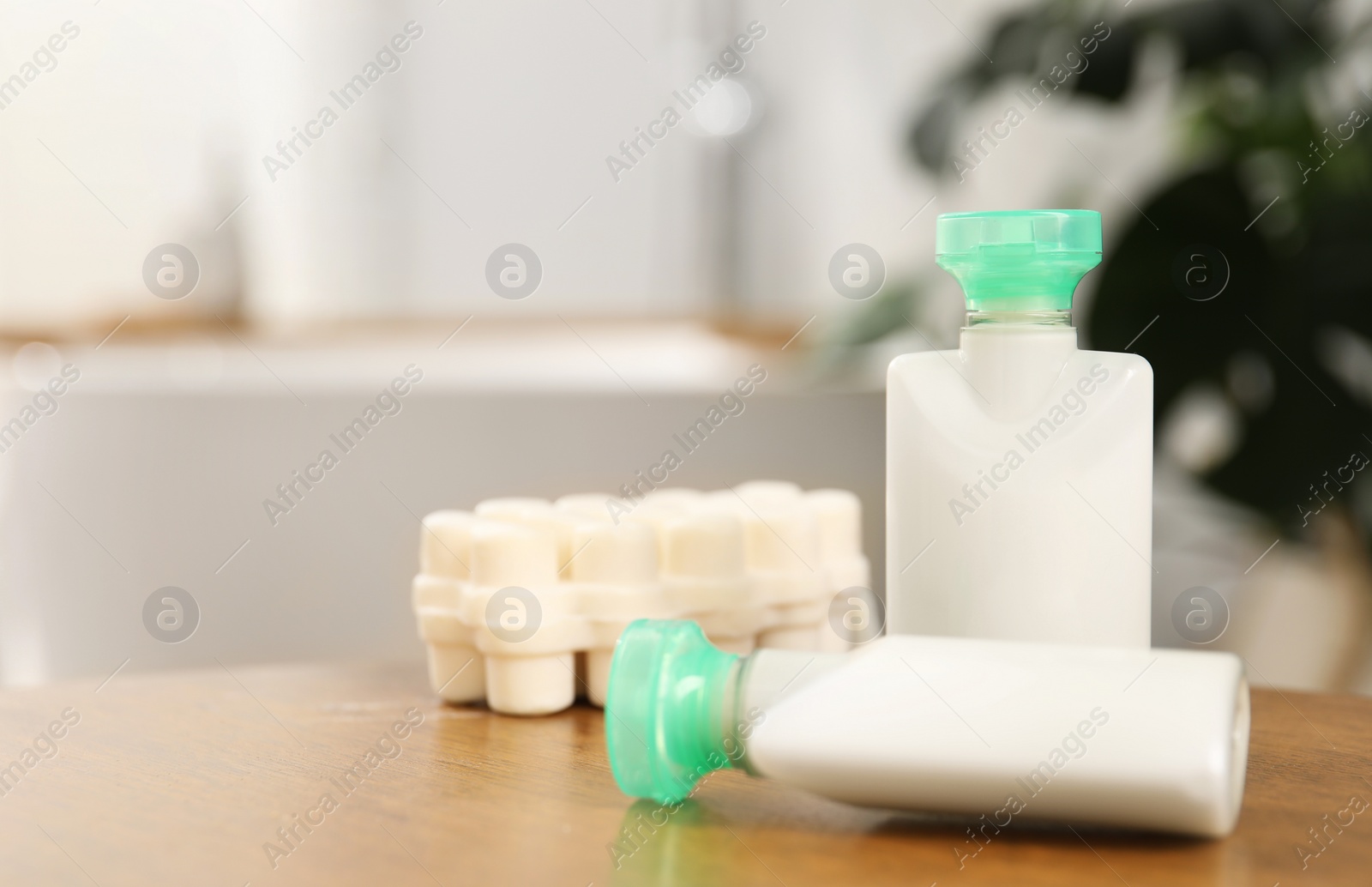 Photo of Mini bottles of cosmetic products and soap on wooden table against blurred background, closeup. Space for text