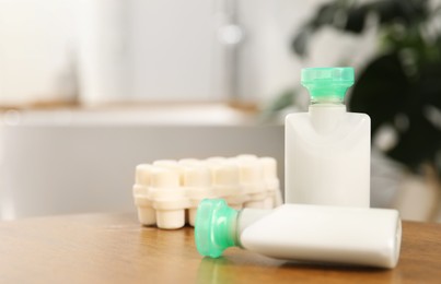 Photo of Mini bottles of cosmetic products and soap on wooden table against blurred background, closeup. Space for text