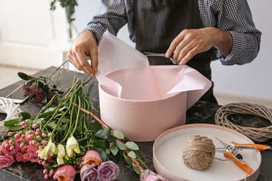 Male florist creating beautiful flower composition at table, closeup