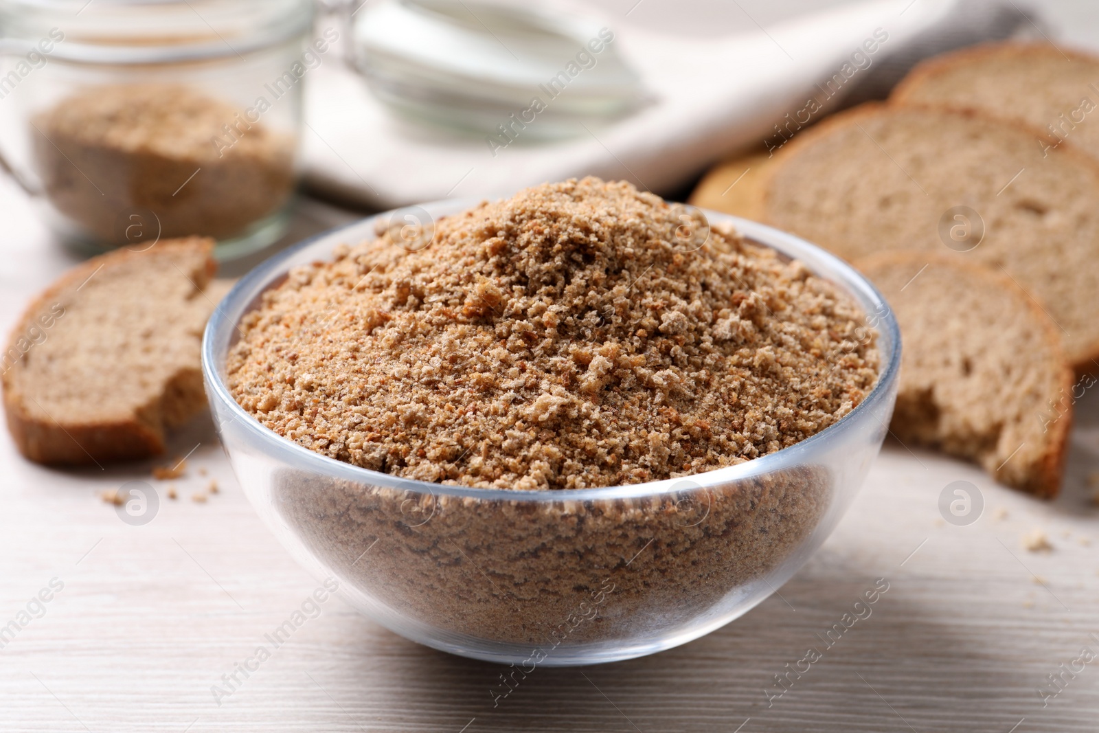 Photo of Fresh breadcrumbs in bowl on white wooden table