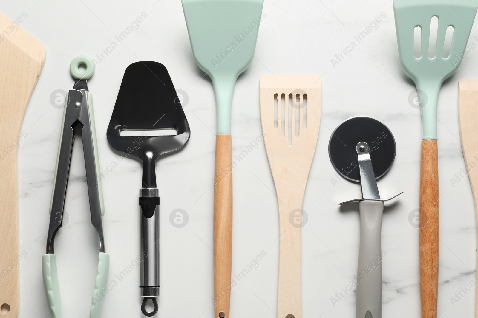 Photo of Different spatulas and other kitchen utensils on white marble table, flat lay