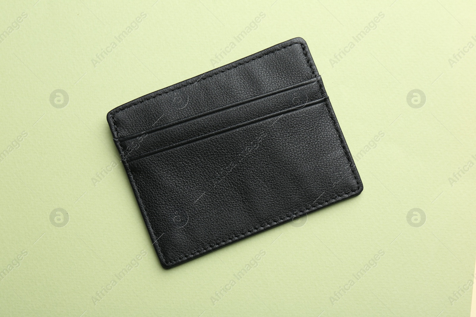 Photo of Empty leather card holder on light green background, top view