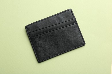 Empty leather card holder on light green background, top view