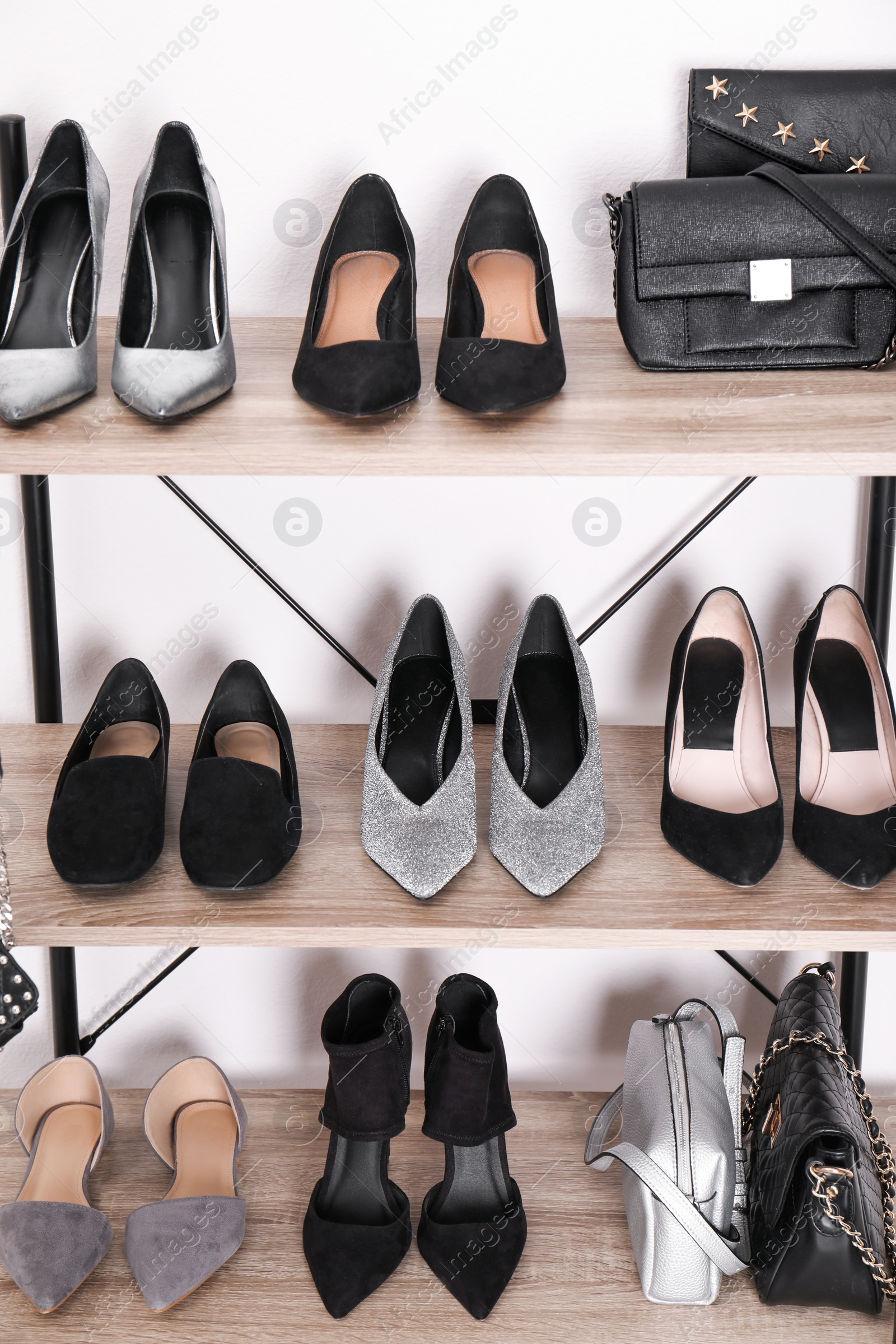 Photo of Shelving unit with stylish shoes and purses near white wall. Element of dressing room interior