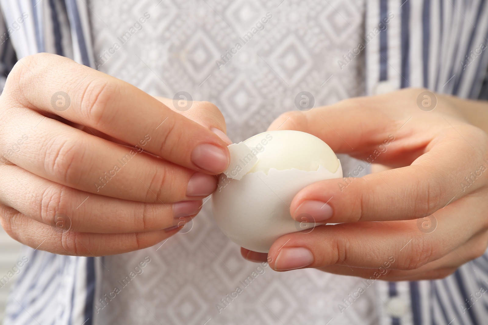 Photo of Woman peeling fresh boiled egg, closeup view