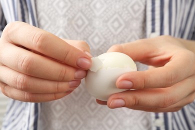 Photo of Woman peeling fresh boiled egg, closeup view