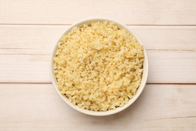 Delicious bulgur in bowl on wooden table, top view