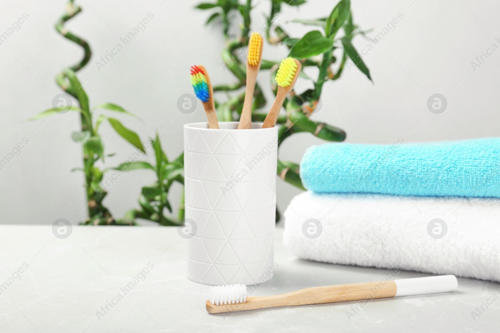 Photo of Bamboo toothbrushes and holder on table indoors. Dental care