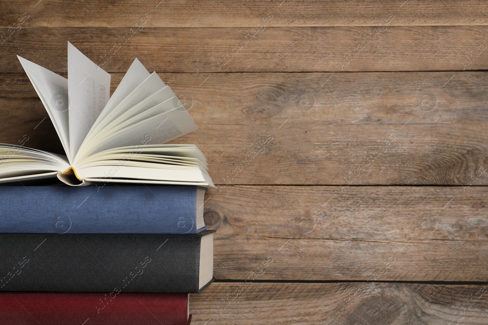 Photo of Stack of hardcover books on wooden table, space for text