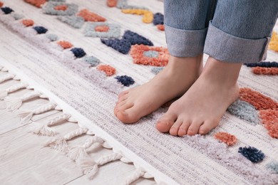 Photo of Woman standing on carpet with pattern at home, closeup