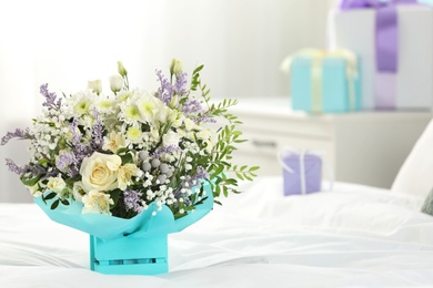 Photo of Beautiful bouquet of flowers in decorative crate on bed. Space for text