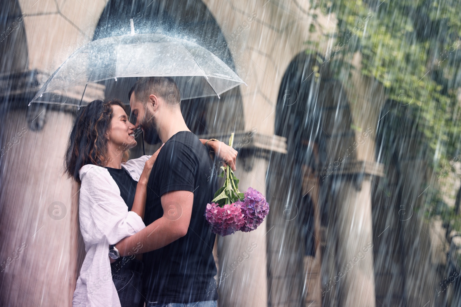 Image of Young couple with umbrella enjoying time together under rain on city street