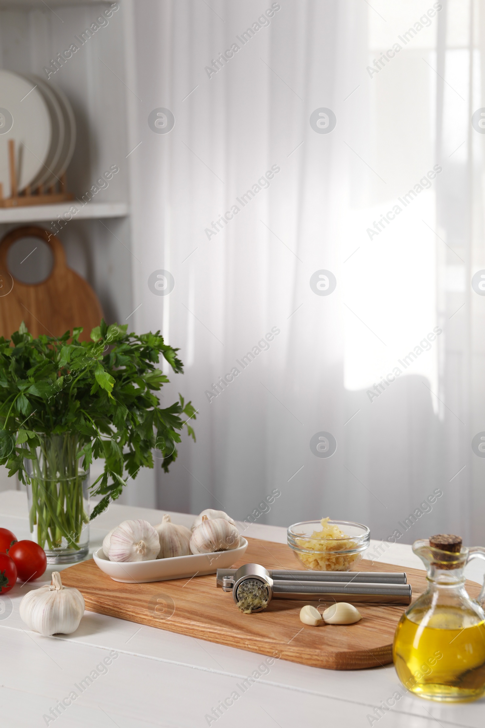 Photo of Garlic press and products on wooden table in kitchen