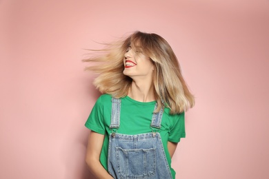 Beautiful young woman with healthy long blonde hair on color background