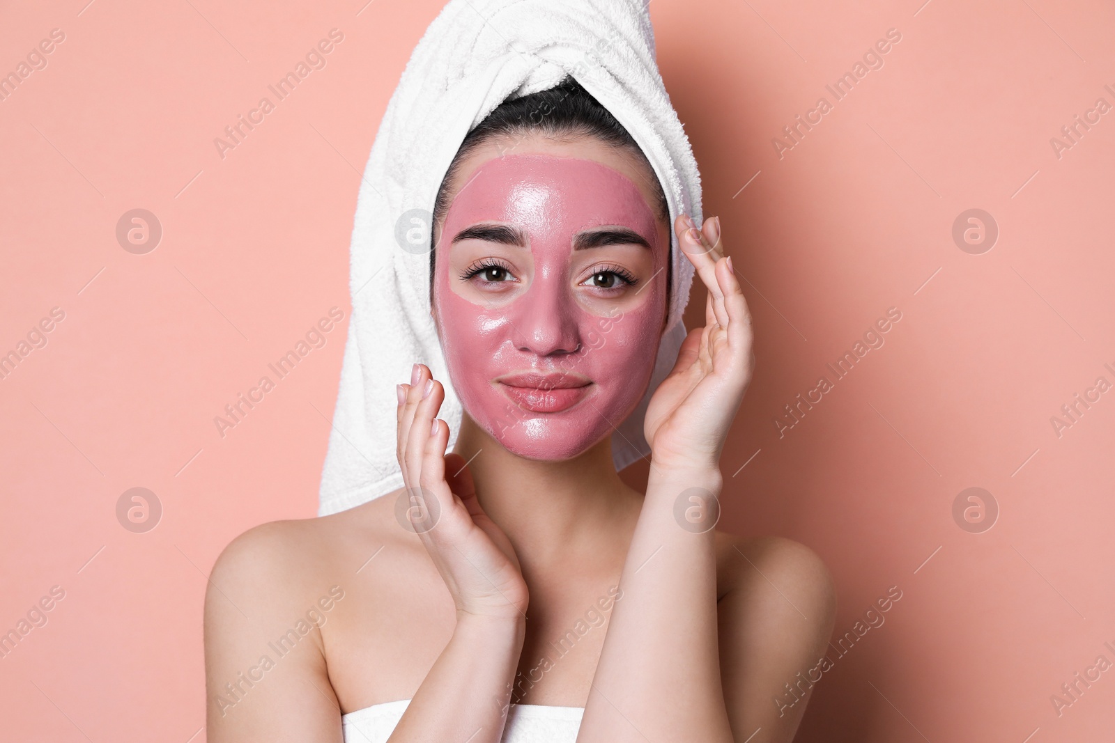 Photo of Woman with pomegranate face mask on pale coral background