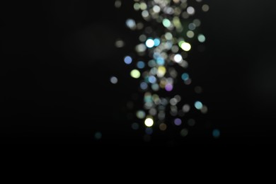 Photo of Blurred view of colorful festive lights on black background. Bokeh effect