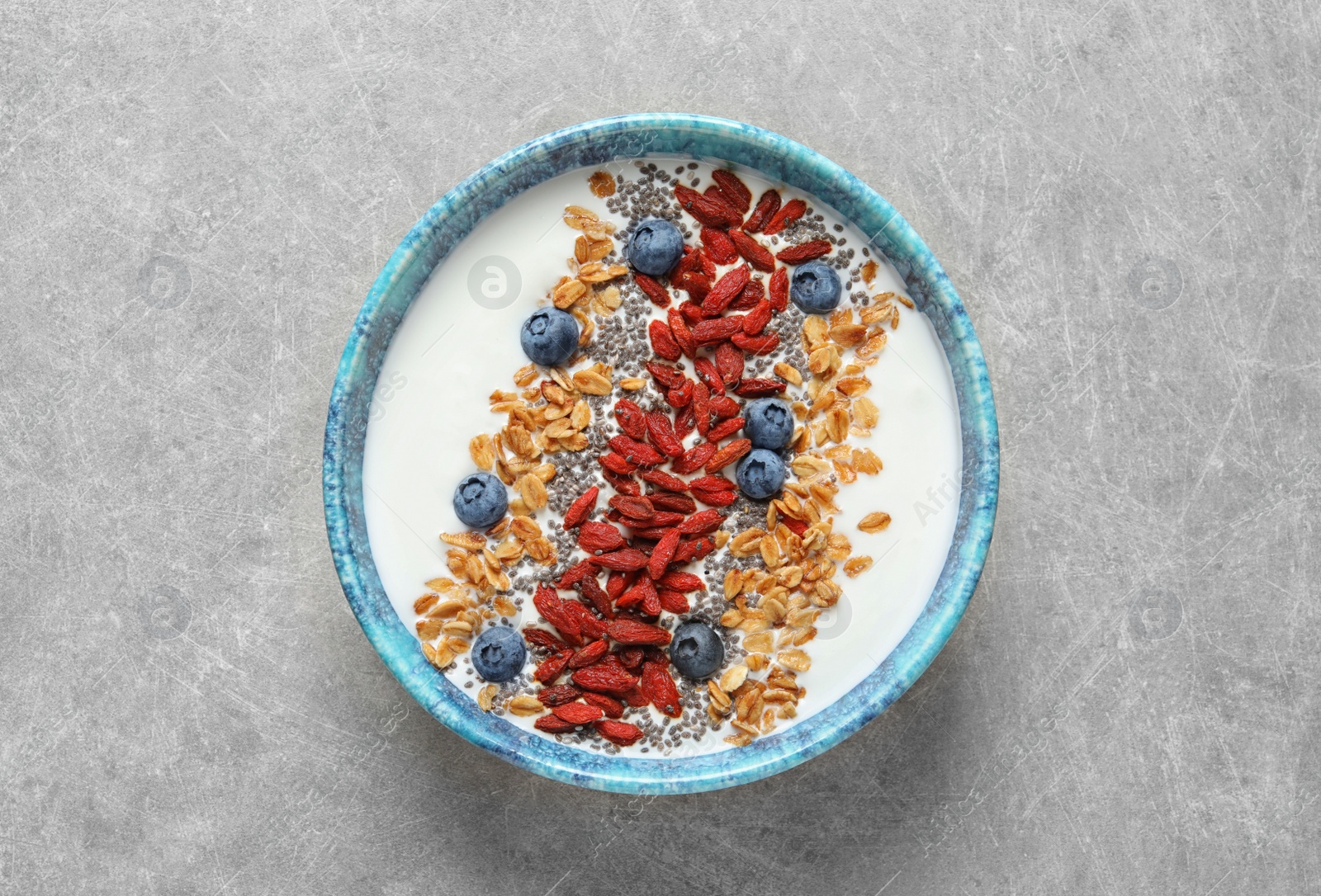 Photo of Smoothie bowl with goji berries on grey table, top view