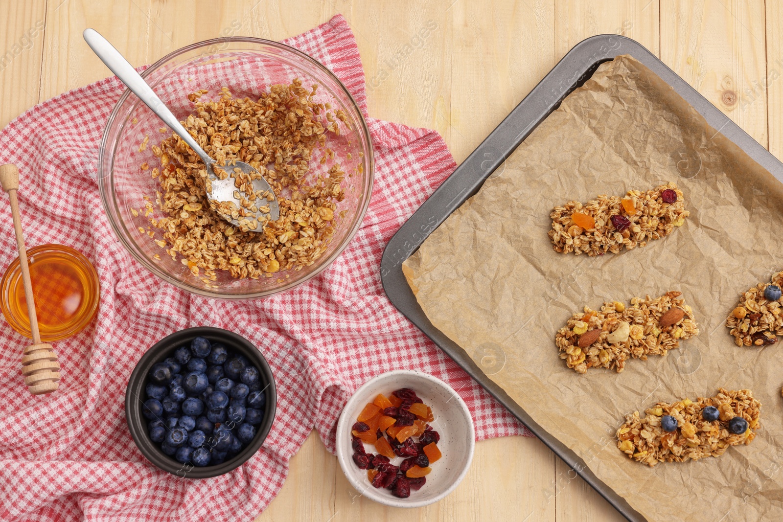 Photo of Making granola bars. Baking tray and ingredients on wooden table, flat lay