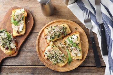 Photo of Delicious bruschettas with fish on wooden table, flat lay