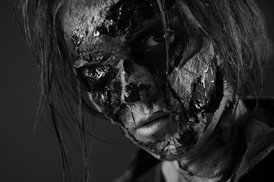 Photo of Scary zombie on dark background, black and white effect. Halloween monster