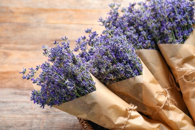 Photo of Fresh lavender flowers in basket on wooden table, closeup view